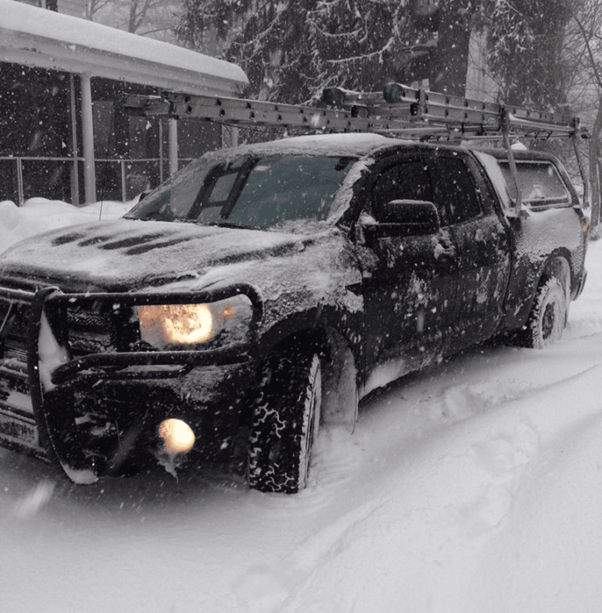 Black truck with roof ladder in snow